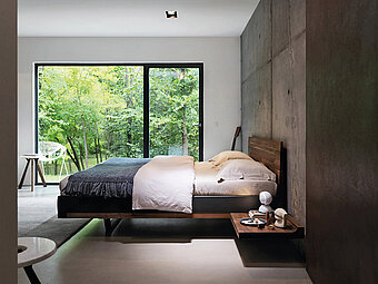 Ein modernes Massivholzbett Riletto von Team 7 mit klaren Linien und einem minimalistischen Design. Das Bett ist aus robustem Nussbaumholz gefertigt und besticht durch seine schlichte Eleganz. Die hochwertige Verarbeitung und das natürliche Material machen dieses Bett zu einem langlebigen und stilvollen Möbelstück.