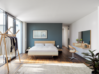 Modernes Schlafzimmer aus Massivholz von Team 7, das Bett hat eine schwebende Optik, der Spiegel und Schminktisch ist perfekt für den Start in den Tag. 